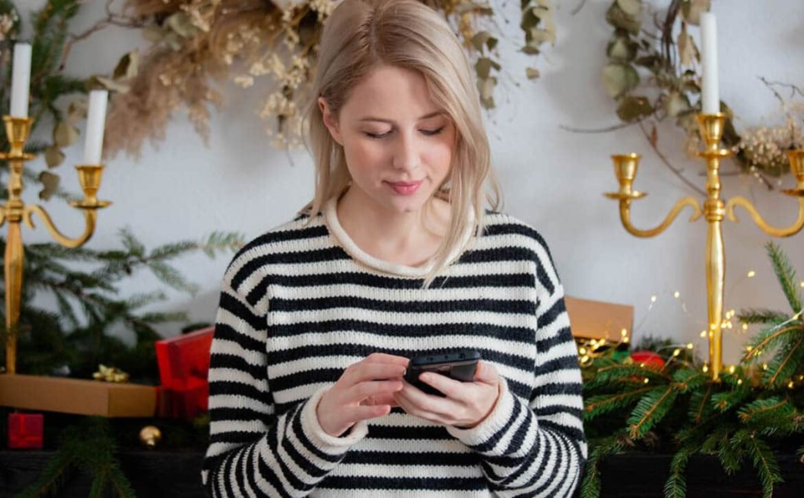 Beautiful woman with mobile phone near Christmas decorated fire