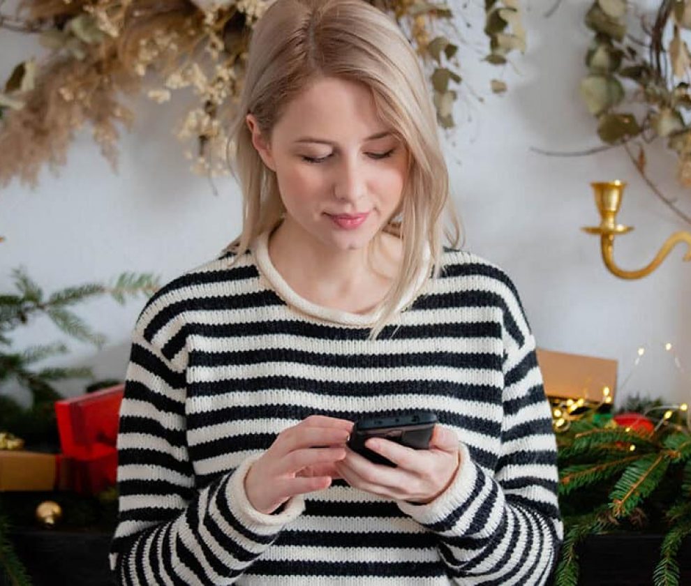 Beautiful woman with mobile phone near Christmas decorated fire